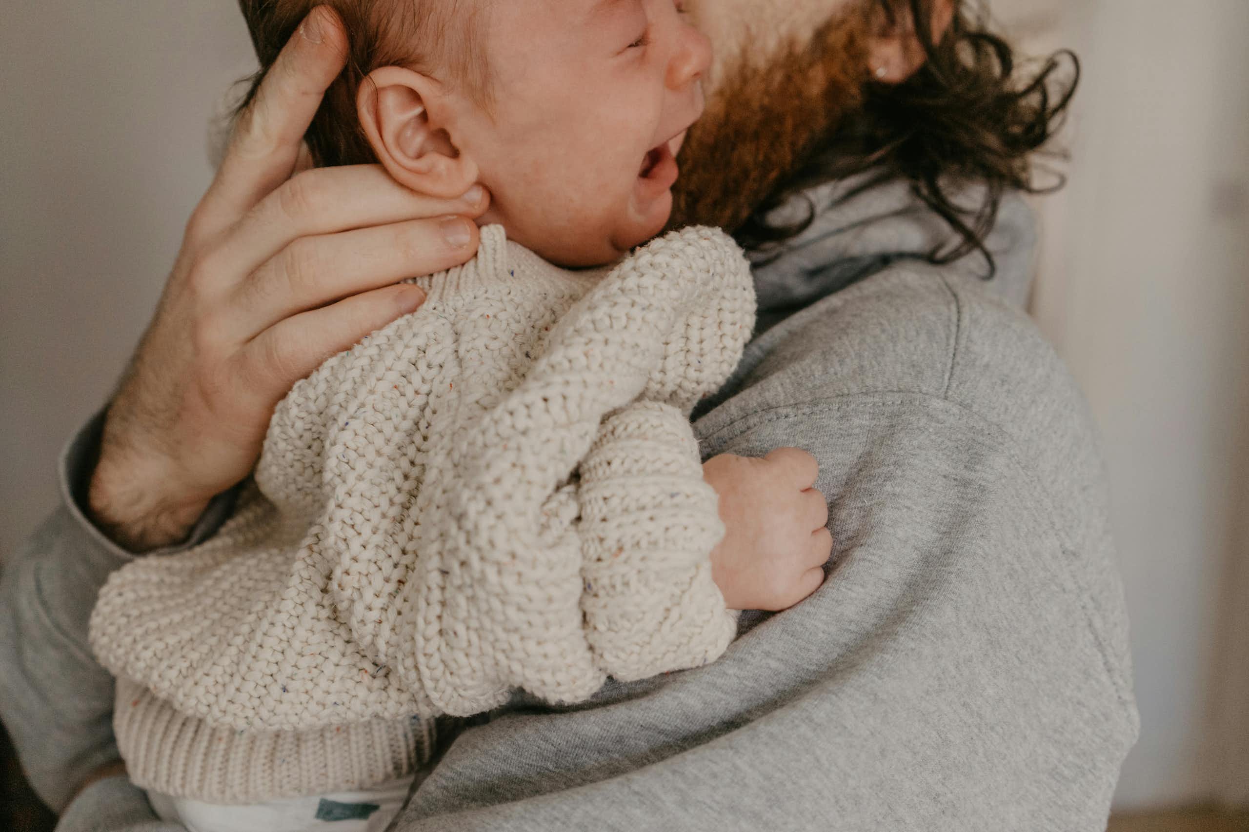 A man is holding a crying baby in his arms.
