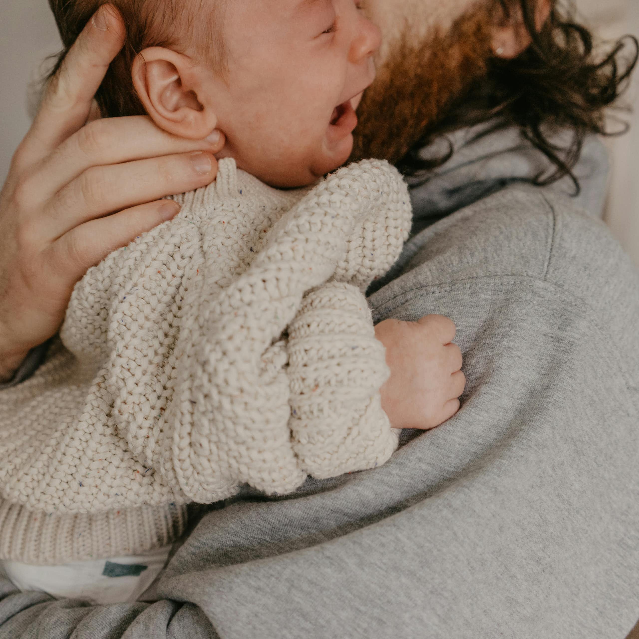A man is holding a crying baby in his arms.