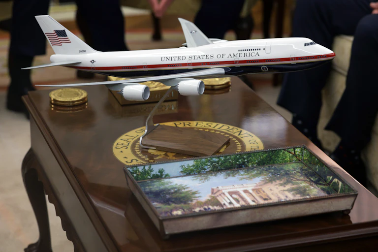 A model of an airplane is seen on a wooden desk.