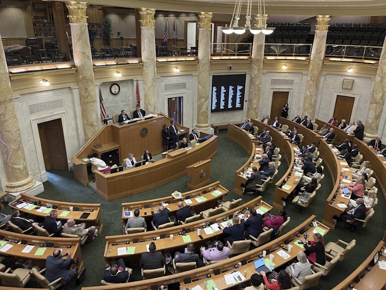 A large room, seen from above, with rows of desks encircling a central podium.