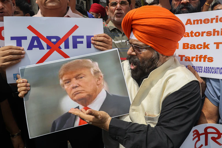 Indians protest against US teriffs, holding up pictures of Donald Trump and signs with the word 'tariff' crossed out.
