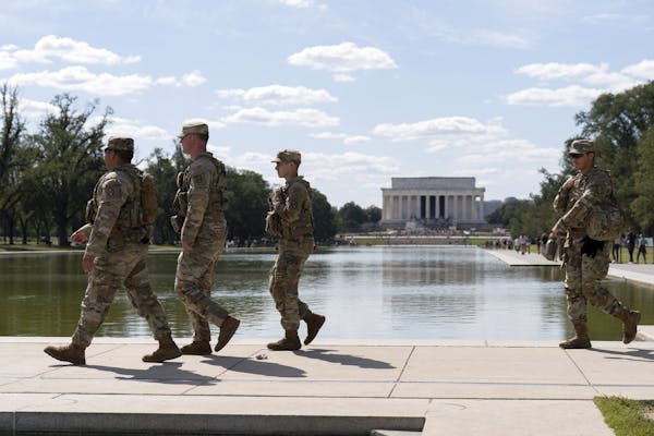 Four soldiers walk along a pool.
