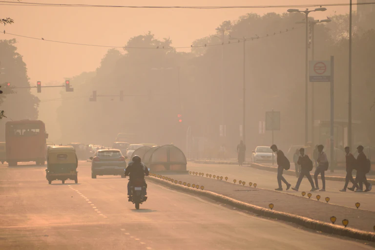 Coches y personas en una carretera cubierta por una niebla ocre