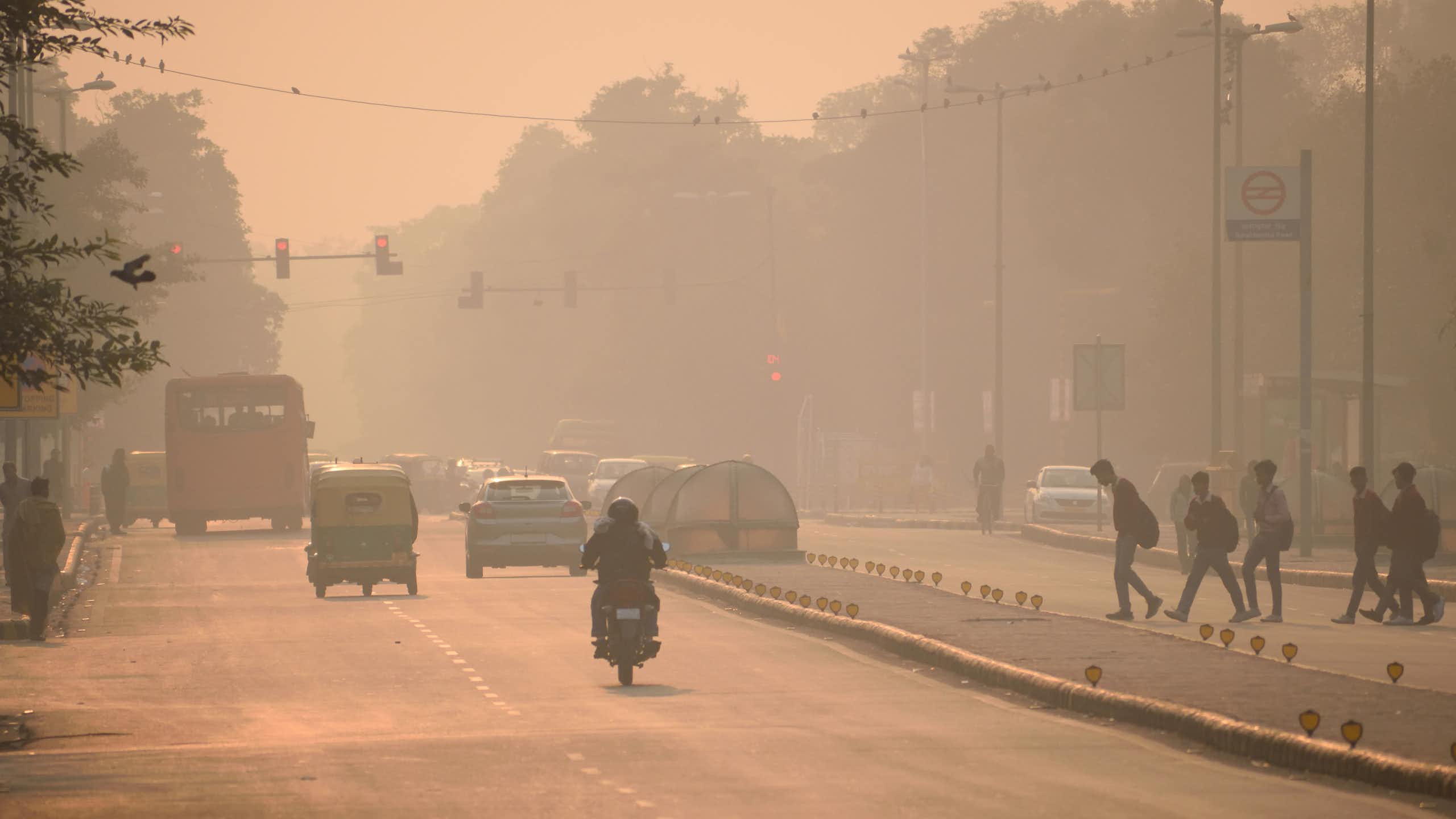 Coches y personas en una carretera cubierta por una niebla ocre