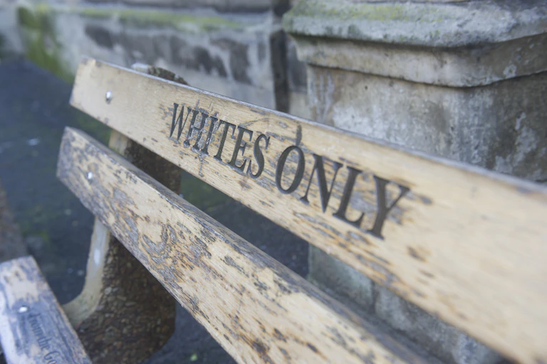The backrest of a bench with the words 'whites only.'