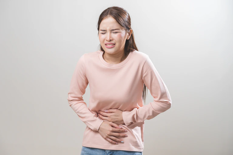 Woman winces with pain while holding her stomach
