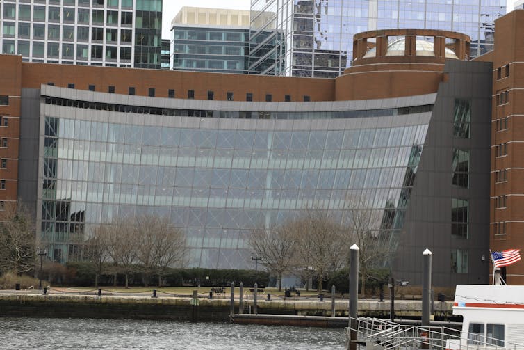 A large, modern building covered in glass that sits on the waterfront.
