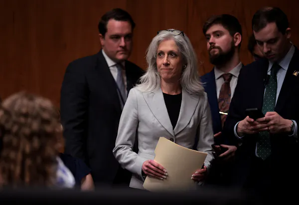 Monarez walks into a room for a confirmation hearing with officials standing behind her.