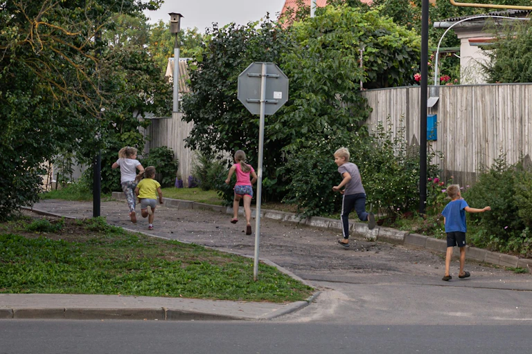 A wide view of a residential street with children of different ages running