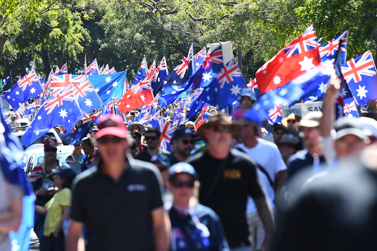 Crowd of March for Australia demonstrators carrying flags