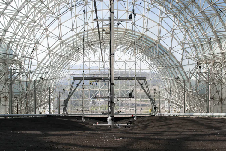 A glass dome with a sloped floor of dark rock.
