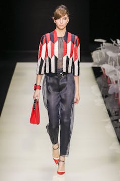 Una mujer desfila con un pantalón negro y una chaqueta colorida.