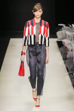 Una mujer desfila con un pantalón negro y una chaqueta colorida.