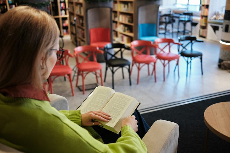 Una persona con un libro en la biblioteca.