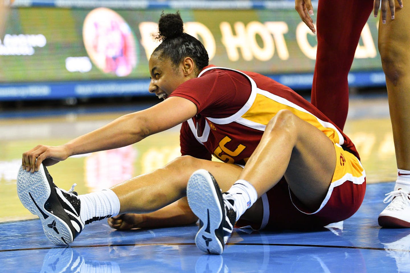 Trojans basketball player JuJu Watkins sitting on the court stretching her leg