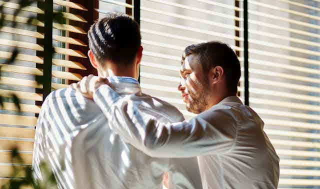 Um homem consola outro homem que está chateado em um escritório.