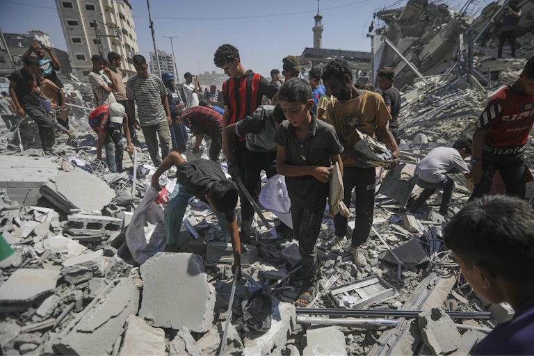 People amidst rubble picking it up and looking around.