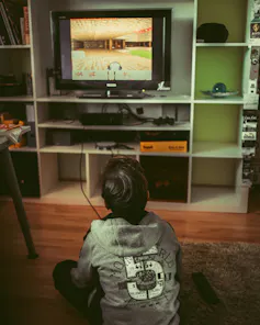 A boy is sitting on the floor playing a video game seemingly alone in front of a television.