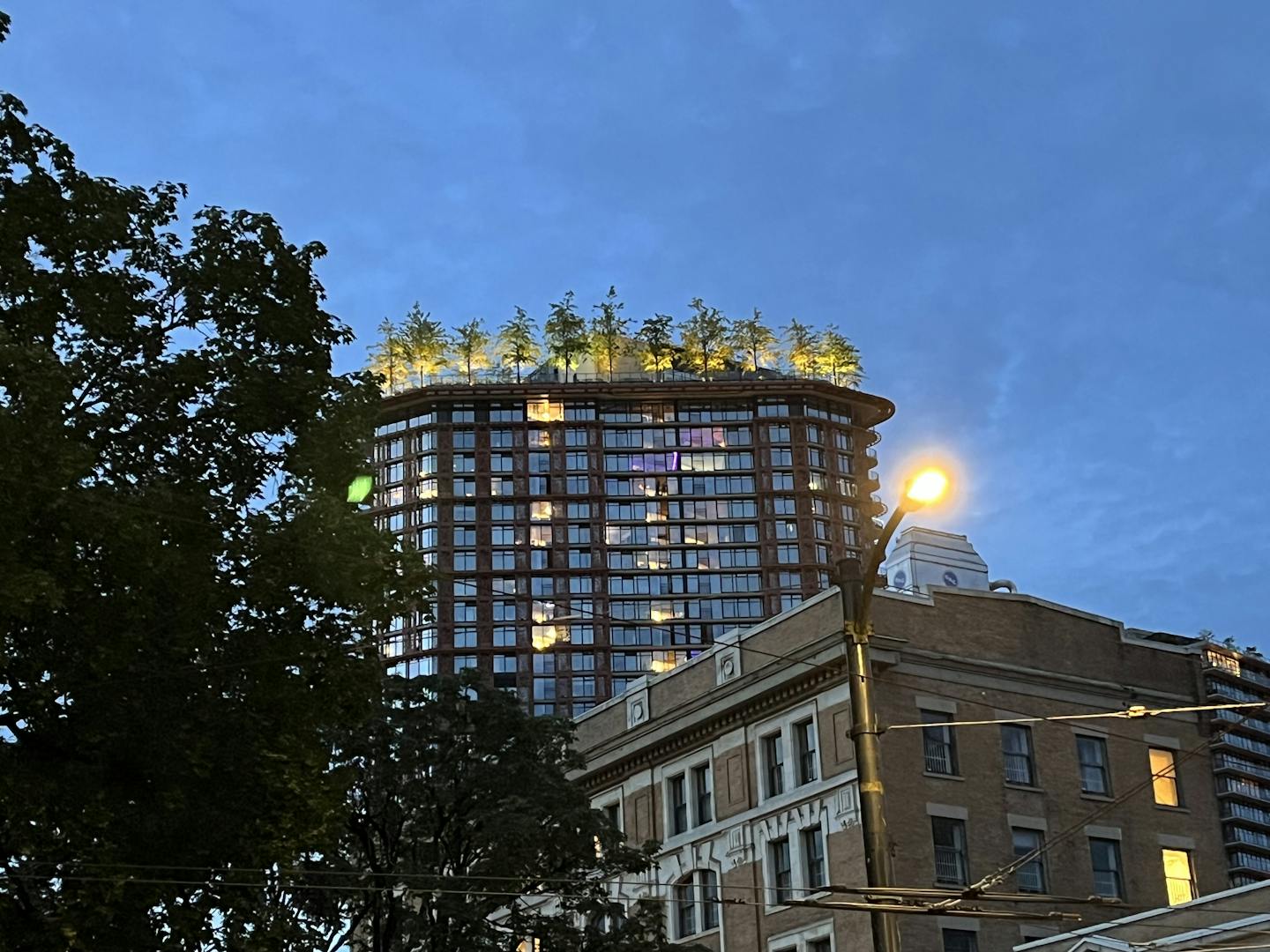 A high-rise building with trees on the roof