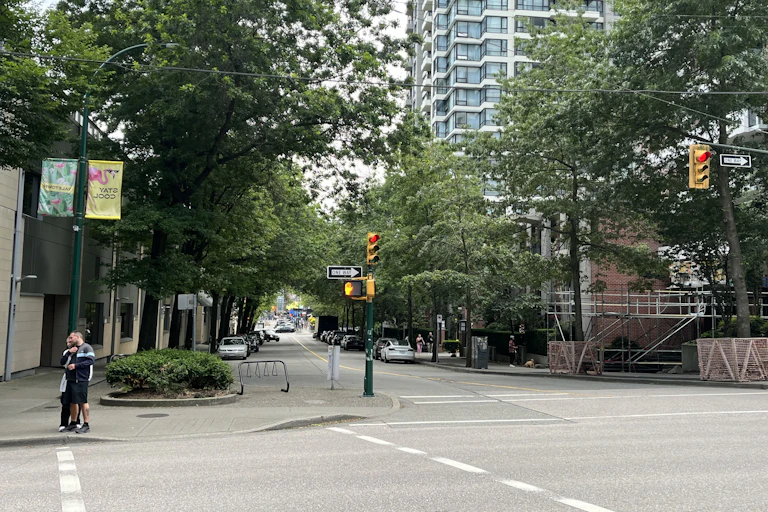 a tree-lined street in an urban area, a tall building in the background