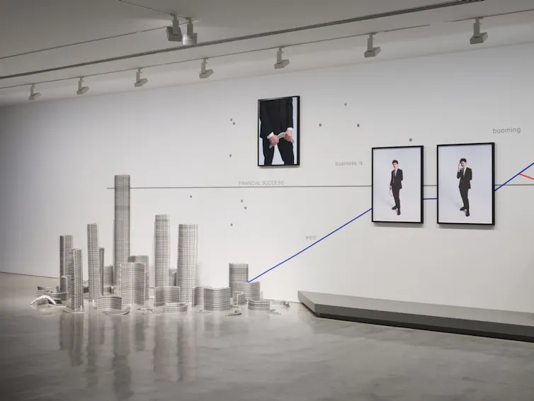 Stacked silver boomerangs, photographs of Williams in business suit mounted on a wall graph