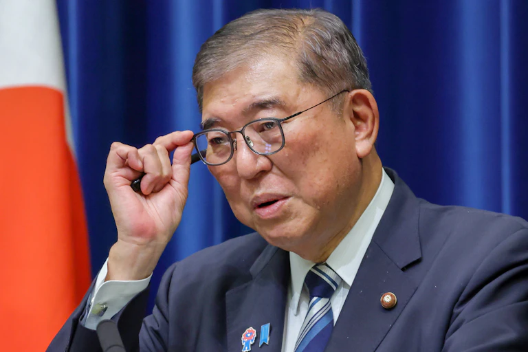 Man in a suit adjusts his spectacles