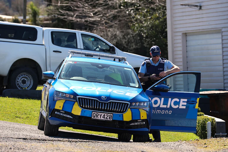 A police officer stands next to his car near a roadblock, following a shootout in New Zealand's Waikato region, where a father who spent nearly four years on the run with his children was killed.