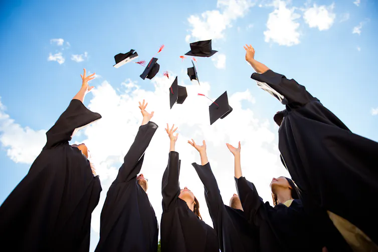 Graduates throw caps into the sky.