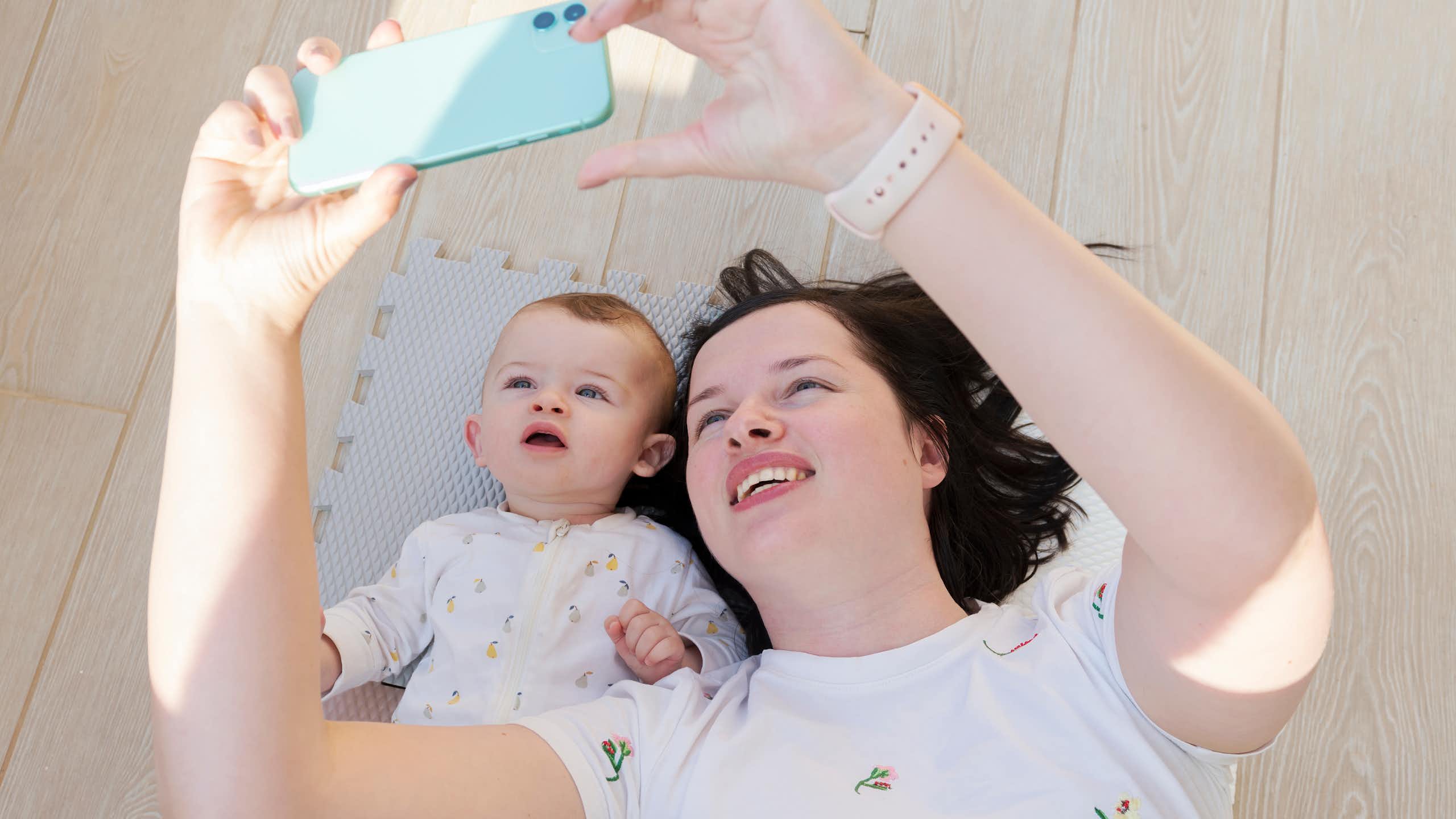 Una mujer mira a un móvil junto a un bebé