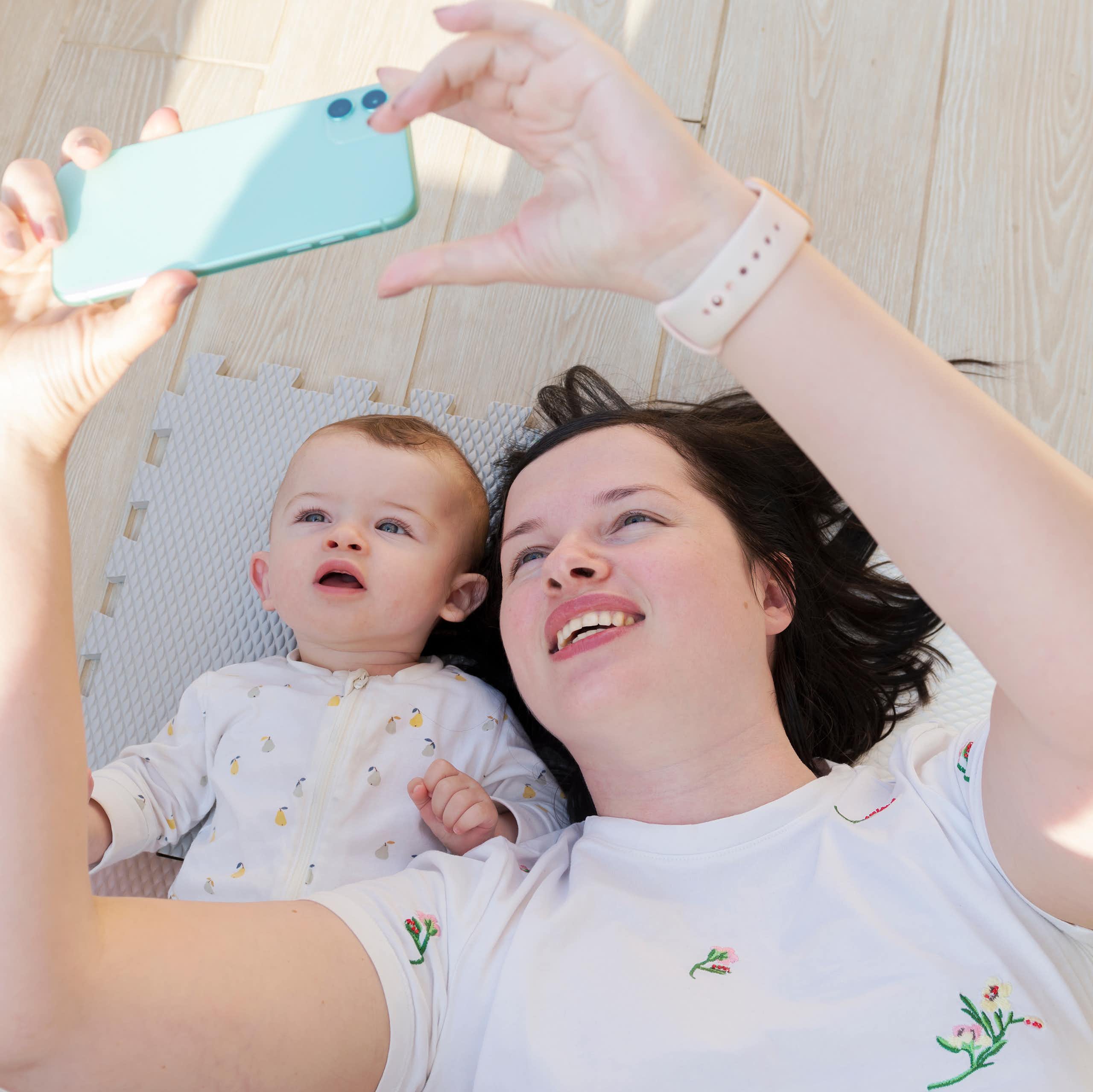 Una mujer mira a un móvil junto a un bebé