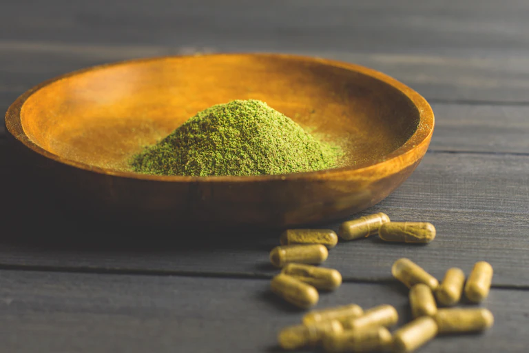 Photographie de poudre de kratom et de gélules.