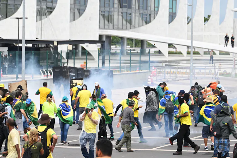 Men and women fill a street with smoke swirling around.