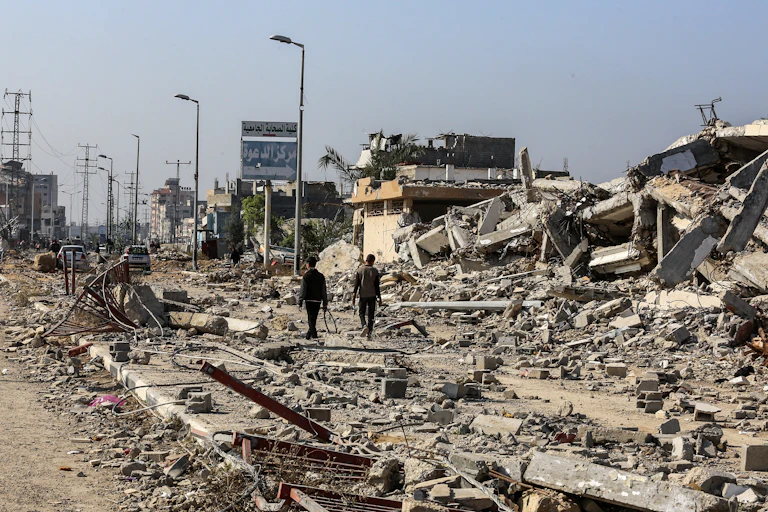 two men walk through destroyed buildings in gaza city.