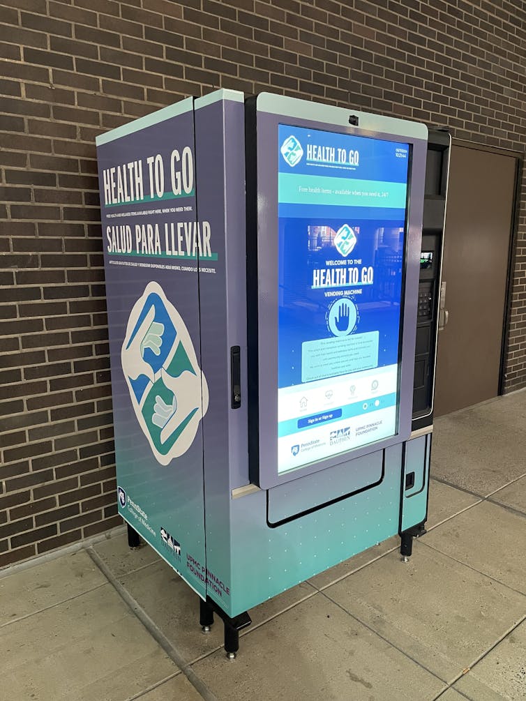 A teal and grey vending machine that says 'Health To Go' with large digital touchscreen on front