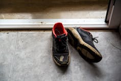A dressed shoe of running shoes sits inside the door frame