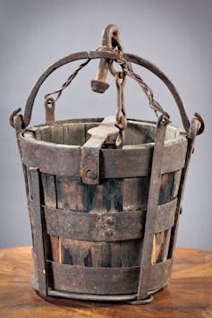 A photo of an old wooden bucket with a metal handle