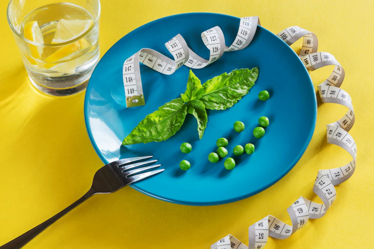 A plate with vegetable greens and an unspooled tape measure.