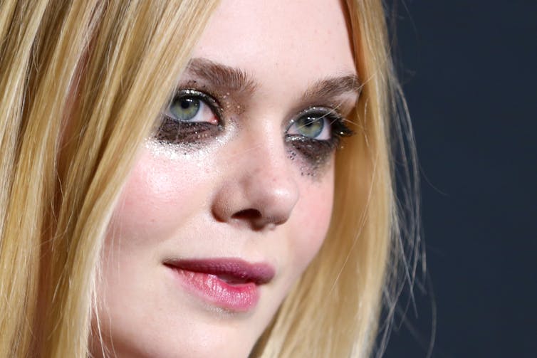 A young woman with heavy, glittery makeup on her eyes and cheeks.