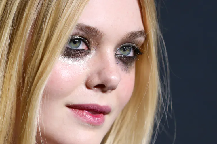 A young woman with heavy, glittery makeup on her eyes and cheeks.