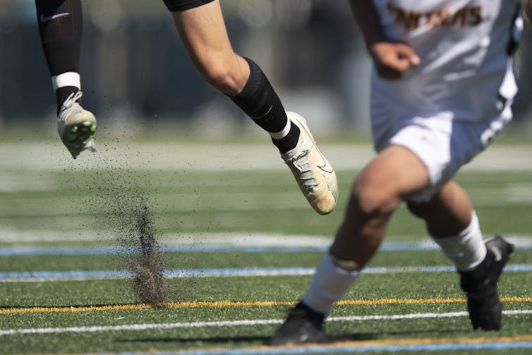 A cloud of tiny particles rises from the turf from where a soccer player just jumped.