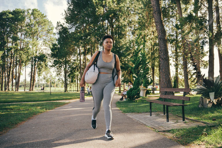 African-Australian woman in gym gear walks in the park