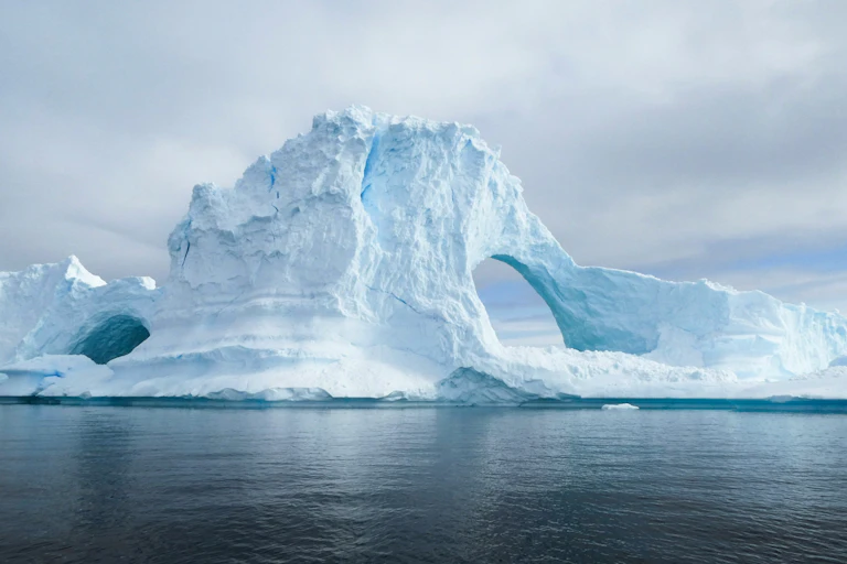 A large ice berg with a hole in it.