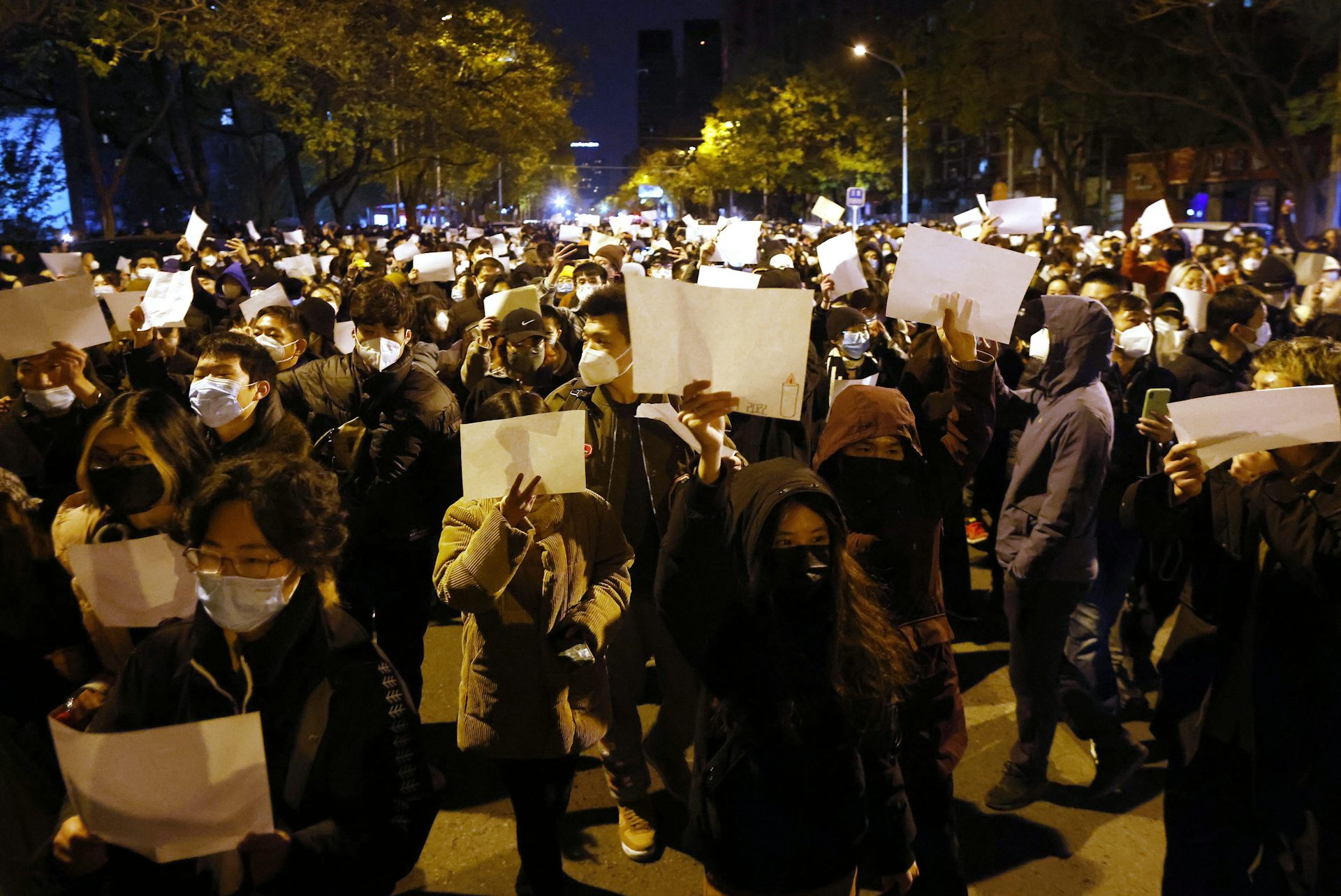 A crowd of Chinese protesters march carrying blank sheets of paper.