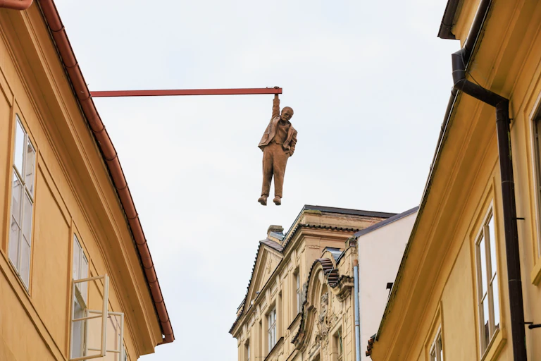 Estatua de un hombre colgando de una viga de un edificio.