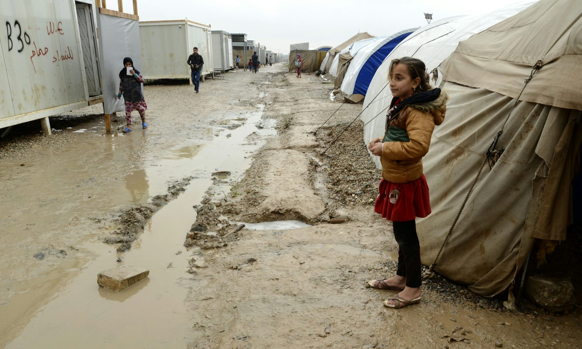 An Iraqi girl stood next to a tent in a flooded displacement camp.