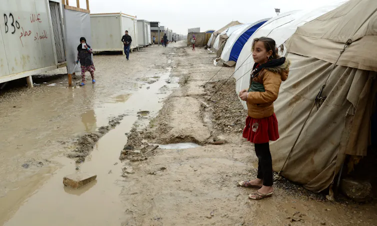 An Iraqi girl stood next to a tent in a flooded displacement camp.