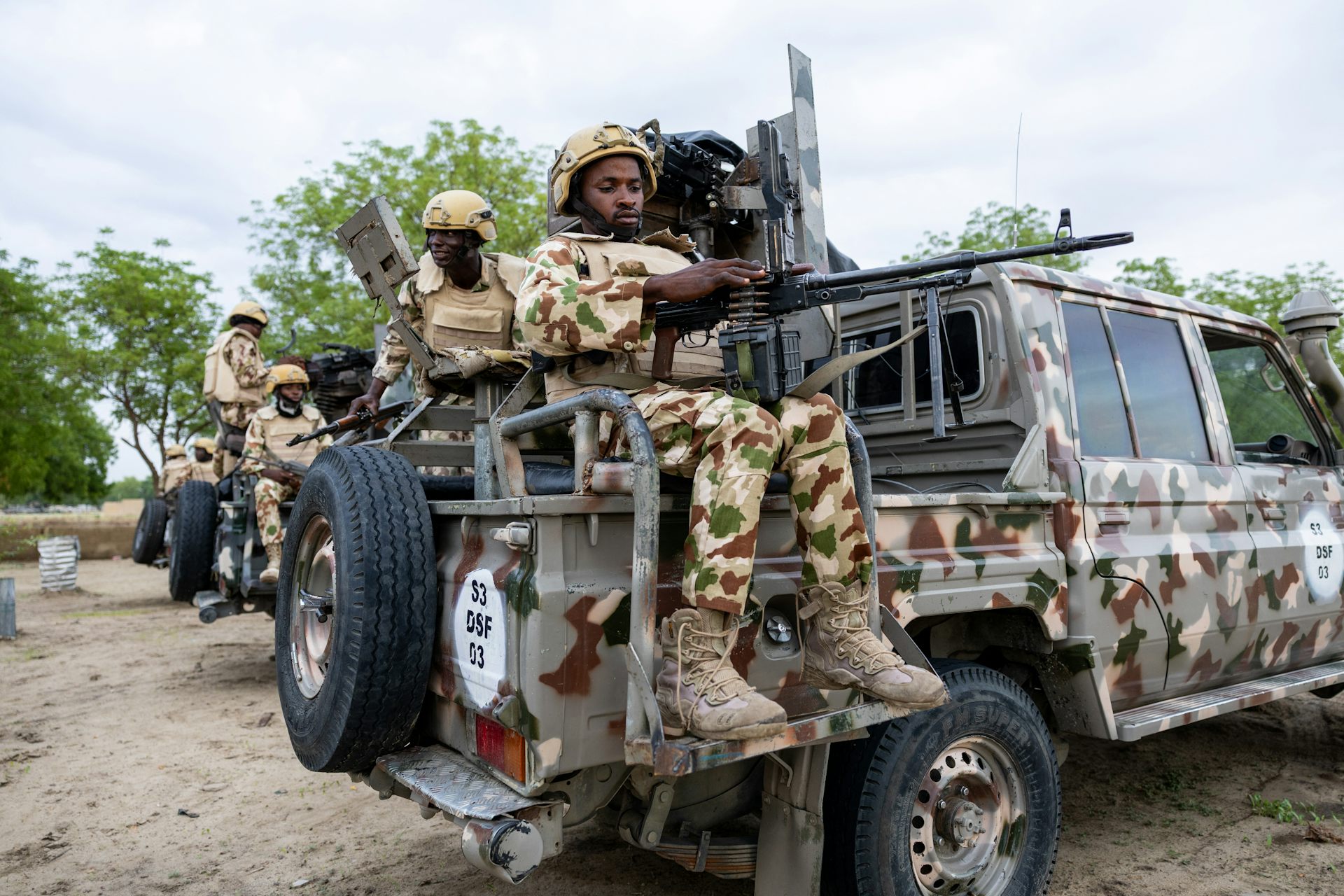 Men in military fatigue seating on the back of gun trucks