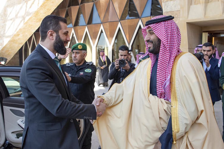 Two men shake hands.