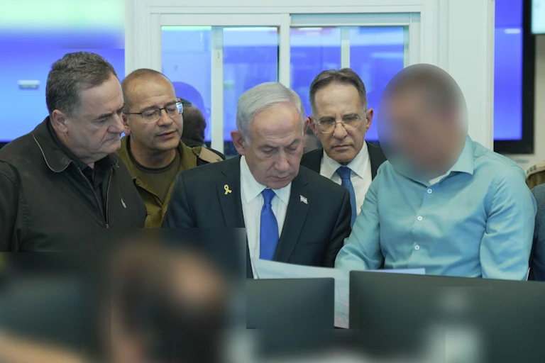 Benjamin Netanyahbu surrounded by government officials look at computer screens. One intelligence officer has his face pixellated.