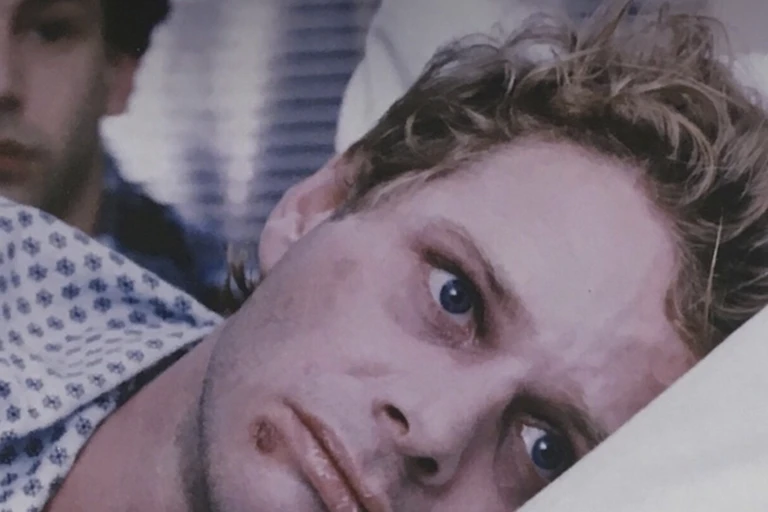 Sickly young man resting his head on a pillow looking forlorn.